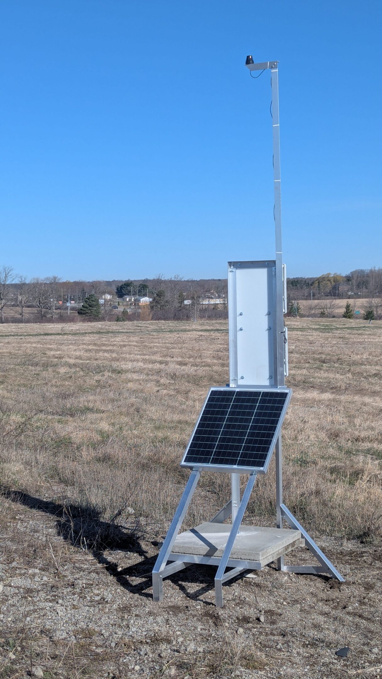 Solar-powered device standing in an open field under a clear sky.
