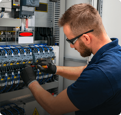 Technician wiring an electrical control panel with precision and care.